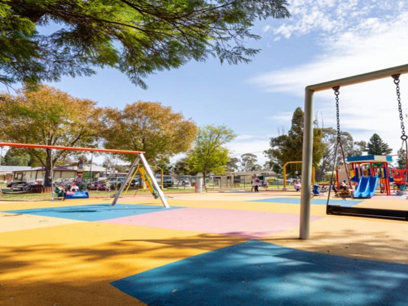 Ein Installateur bereitet einen verdichteten Schotterunterbau vor, bevor er Gummispielplatzplatten verlegt.